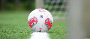 Balón de fútbol en línea de gol como símbolo del deporte popular