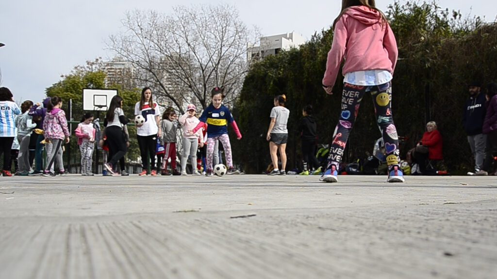 Niñas jugando al fútbol en espacio urbano escolar